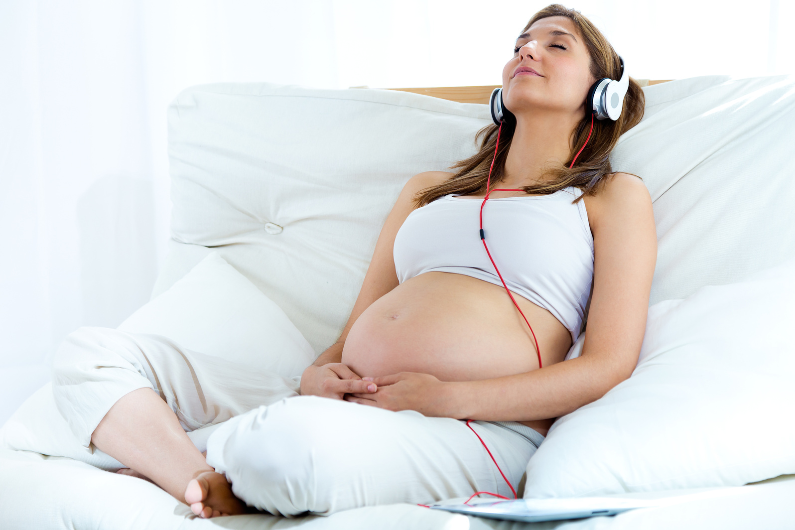 Pregnant Woman Listening to Music on the Bed